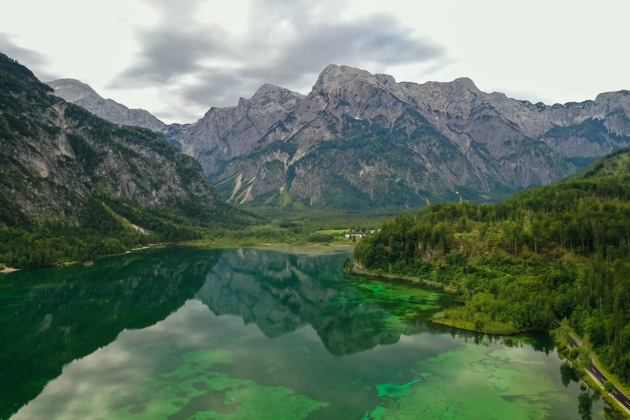 Bergsee mit klarem, grün schimmerndem Wasser vor bewaldeten Ufern und einem Kalksteinmassiv